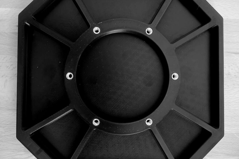 Octagonal additively manufactured plate with radial ribs, central bore and brass threaded inserts.